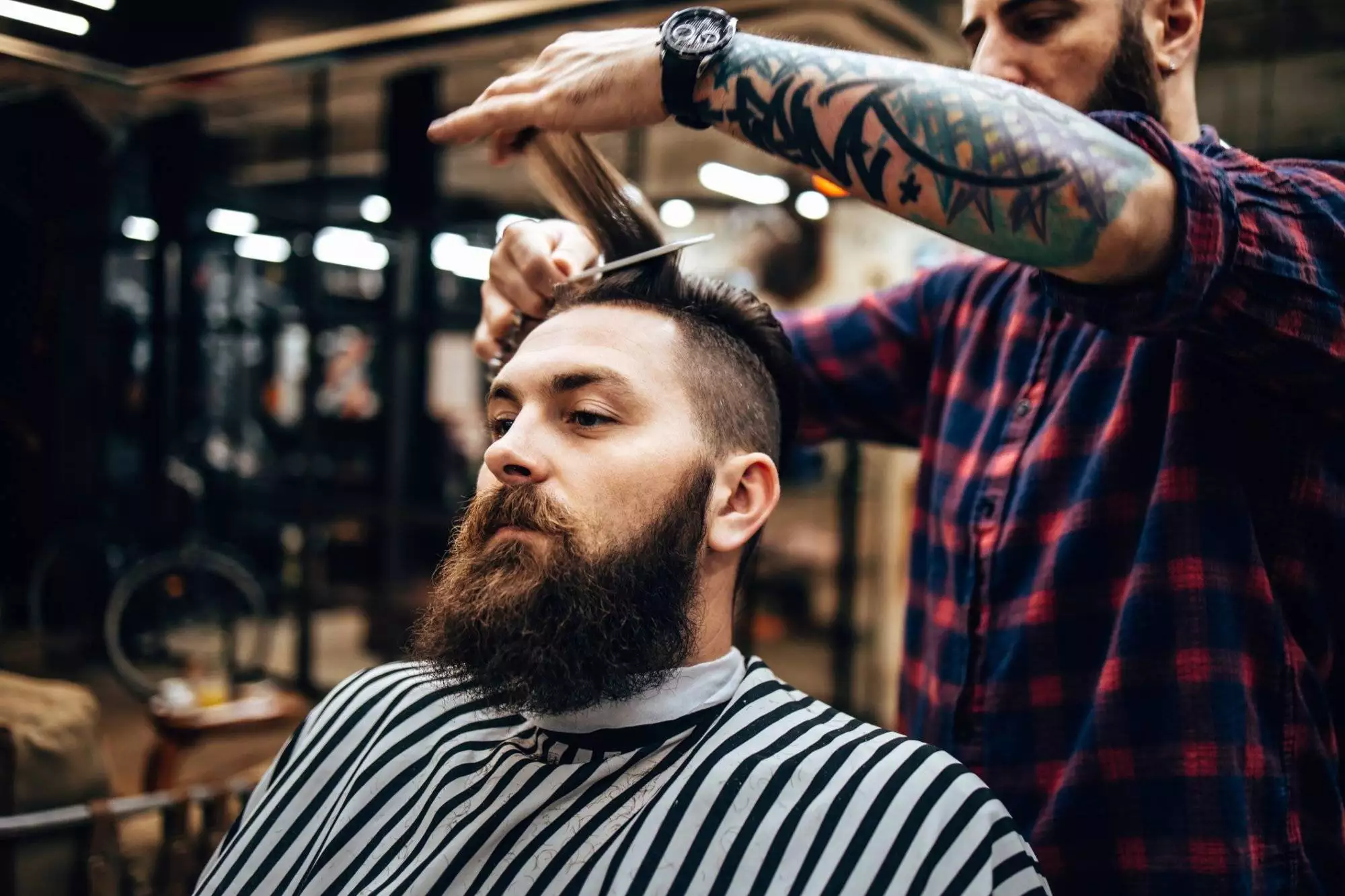 Handsome middle age man receiving hair cutting and styling treatment in a vintage barber shop.